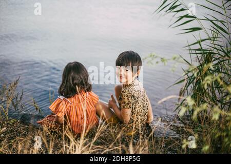 Portrait of smiling girl with down syndrome sister sitting near lake Stock Photo
