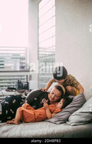 Down syndrome daughter using smart phone by mother and sister on sofa at home Stock Photo