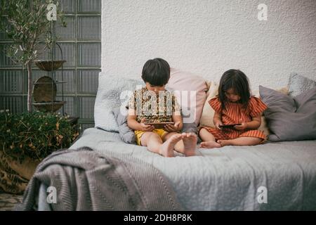 Sister with disability by sibling using smart phones while sitting on sofa at home Stock Photo