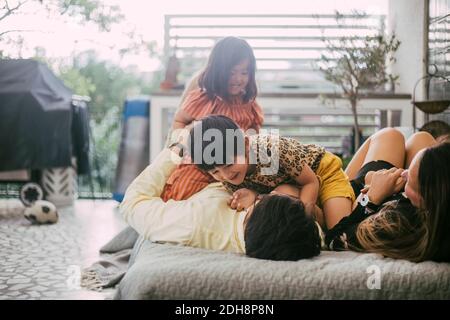 Smiling daughters enjoying with parents on sofa at home Stock Photo