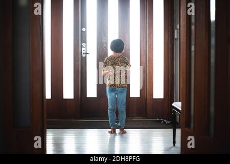 Girl using digital tablet while standing against door at home Stock Photo