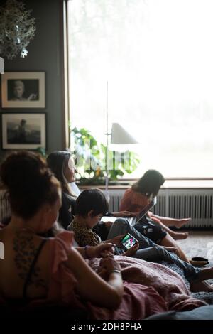 Mother sitting with daughters on sofa in living room Stock Photo