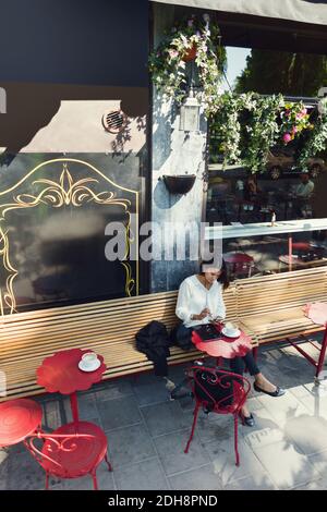 Businesswoman using smart phone at sidewalk cafe Stock Photo