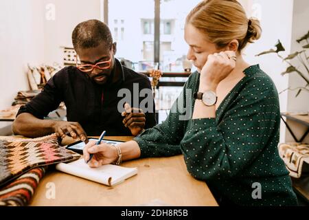 Male employee and female owner working while using digital tablet in store Stock Photo