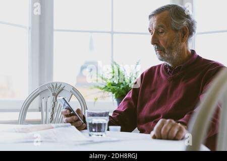 Senior man using smart phone at home Stock Photo