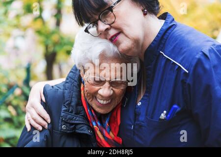 Caretaker embracing senior woman in park Stock Photo