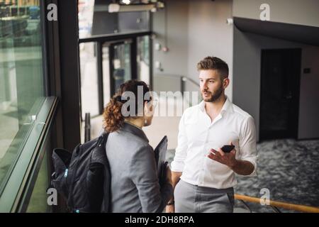 Business professionals discussing in corridor at workplace Stock Photo