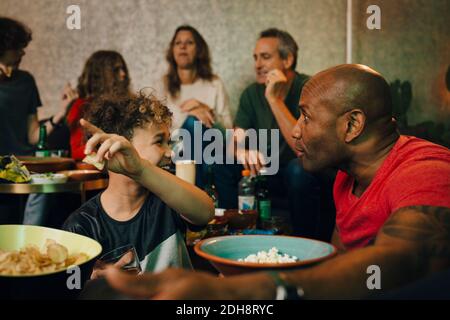 Smiling boy pointing while talking to mature man during sporting event Stock Photo