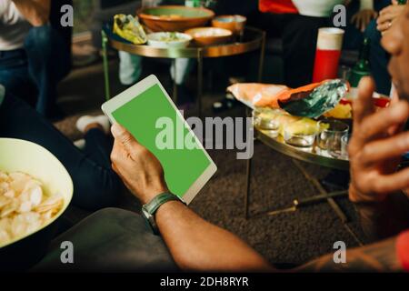 Cropped hand of man using digital tablet during sporting event at night Stock Photo
