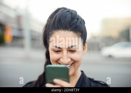 Happy young woman using smart phone in city Stock Photo