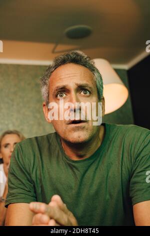 Mature man praying while watching sports in living room Stock Photo