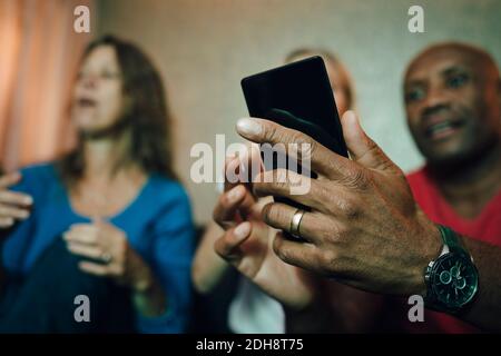 Smiling man showing mobile phone to women during sporting event Stock Photo