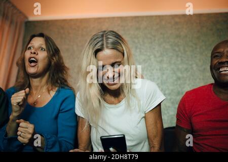 Smiling woman using smart phone by friends during sporting event Stock Photo