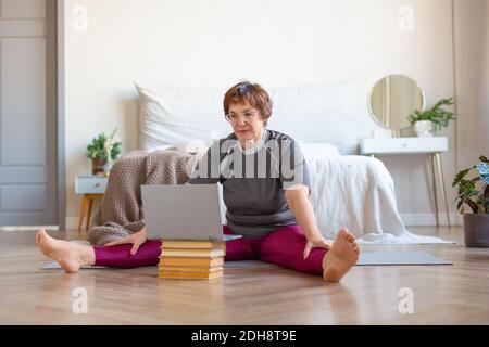 Senior woman having online video call with a coach before pilates workout at home. The concept of a healthy lifestyle. Stock Photo