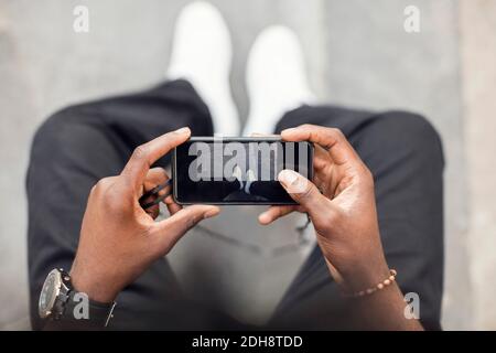 High angle view of man photographing legs on mobile phone Stock Photo
