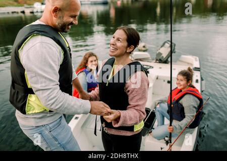 Daughters looking at parents holding hands while sitting in boat Stock Photo