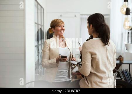 Happy businesswomen talking while standing in office Stock Photo