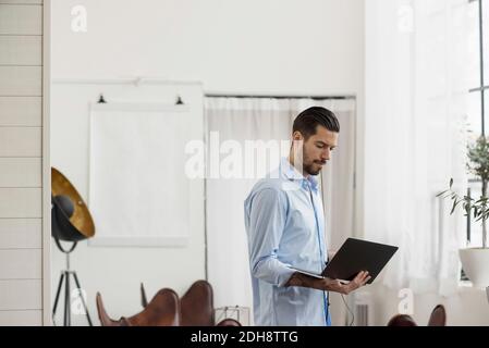 Businessman using laptop while standing at table in office Stock Photo