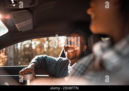 Smiling man looking at female friend in car during road trip Stock Photo