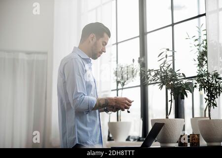Businessman using laptop while standing at table in office Stock Photo