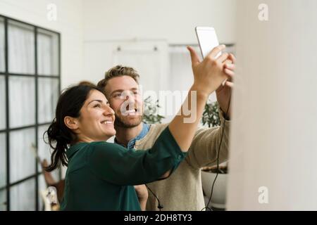Smiling business people taking selfie while standing in office Stock Photo