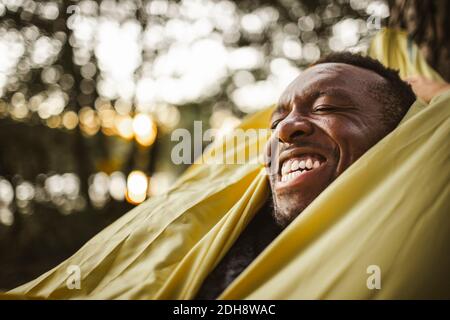 Cheerful man lying over hammock in forest Stock Photo