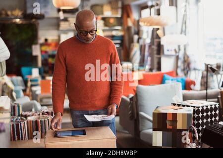Senior man using digital tablet while reading document at store Stock Photo
