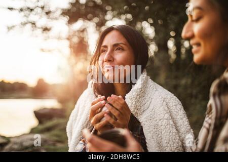 Female friends talking while drinking coffee in forest Stock Photo