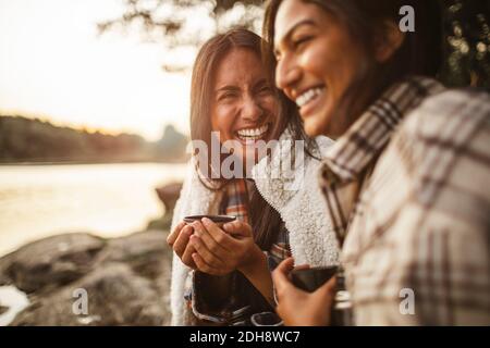 Cheerful female friends talking while drinking coffee in forest Stock Photo