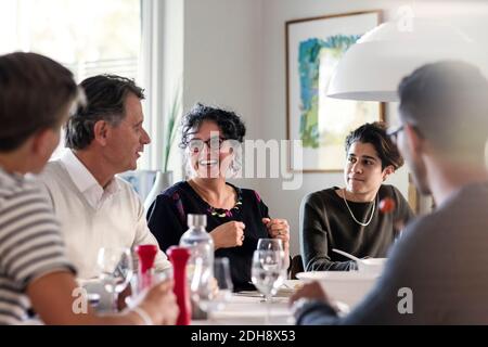 Happy friends discussing at dining table in dinner party Stock Photo