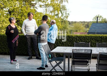 Multi-ethnic friends talking while standing by table in yard Stock Photo