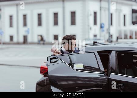 Businessman with smart phone sitting in car Stock Photo