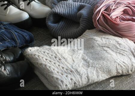 A set of fashionable winter women's clothing. Wool sweater, shoes, jeans, coat, hat and scarf on white wooden background. Stock Photo