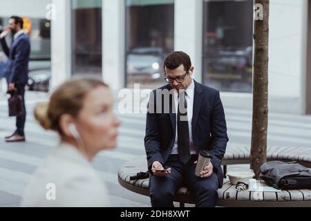 Entrepreneur using mobile phone while sitting in city Stock Photo
