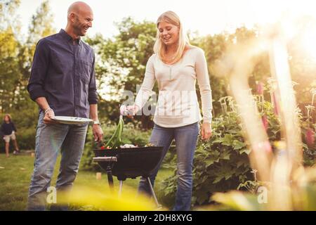 Happy father and daughter cooking vegetables on barbecue grill in back yard Stock Photo