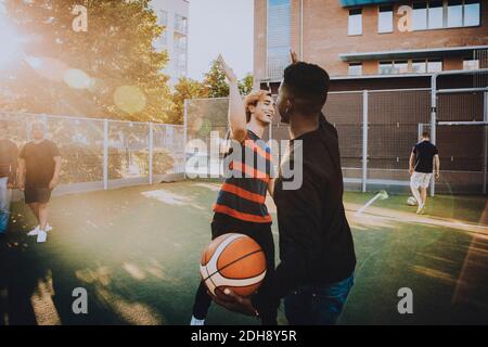 Smiling friends giving high-five while playing sports in field Stock Photo