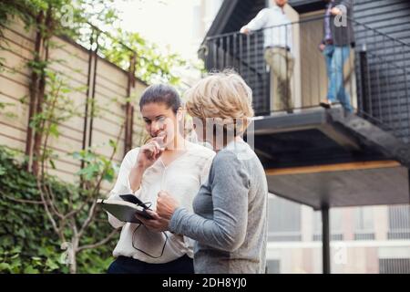 Businesswomen discussing over digital tablet at office yard Stock Photo