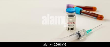 Coronavirus vaccine and syringe on a white background. with blood tubes at the back. horizontal focus. copy space. text area Stock Photo