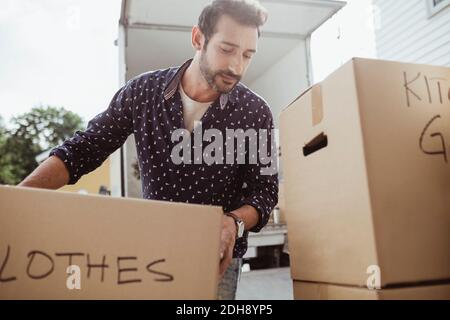 Man unloading cardboard boxes outside van Stock Photo