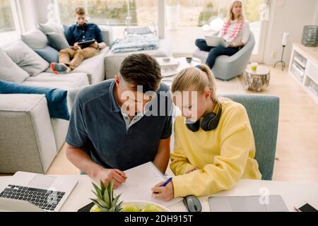 High angle view of father teaching daughter while sitting at table in living room Stock Photo