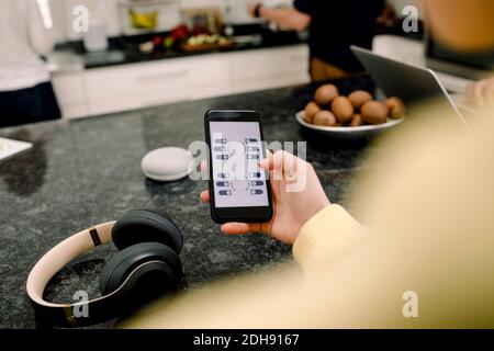 High angle view of girl using mobile phone at kitchen counter Stock Photo
