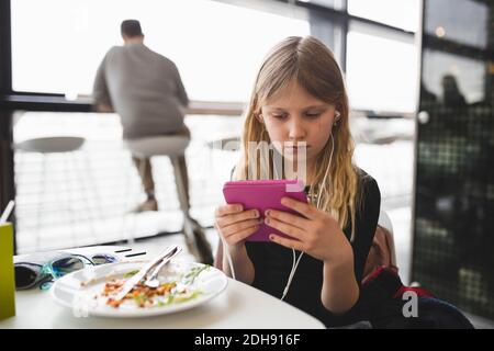 Girl using digital tablet while sitting at table in restaurant Stock Photo