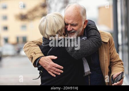 Smiling senior man embracing partner during winter in city Stock Photo