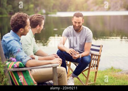 Friends talking while having drink at lakeshore Stock Photo
