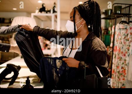 Side view of woman in protective mask buying clothes at fashion store Stock Photo