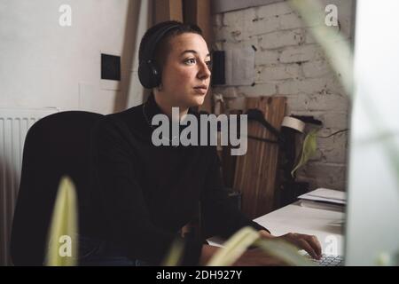 Businesswoman with headphones working on computer at workplace Stock Photo