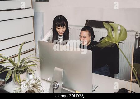 Smiling entrepreneurs working on computer at place of work Stock Photo