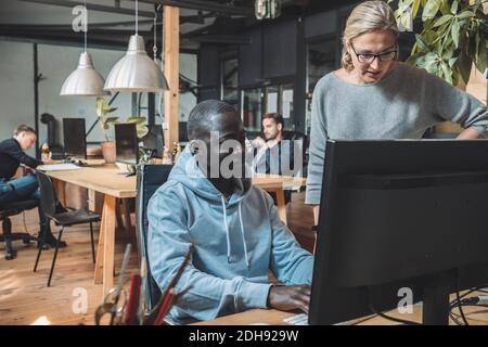 Businessman by female colleague working on computer at workplace Stock Photo