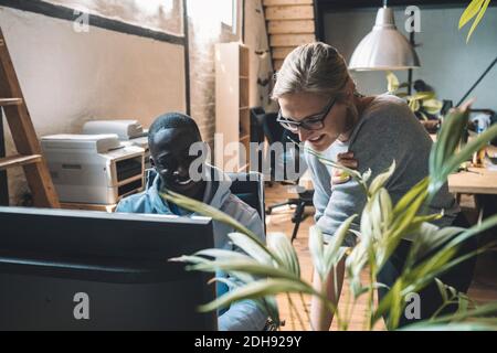Smiling businessman by colleague working on computer at workplace Stock Photo
