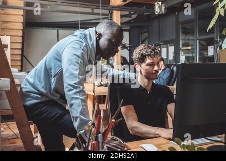 Businessman by colleague working on computer at workplace Stock Photo
